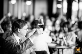 A guest raises his glass during a toast at District Winery in Washington, DC, adding energy to the reception celebration with friends cheering around him.